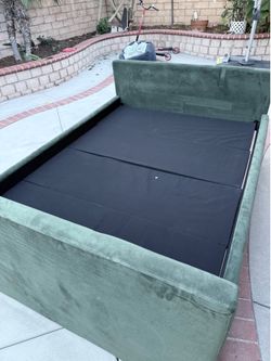 Mdern upholstered velvet platform bed with a hidden footboard storage drawer in dark/emerald green.