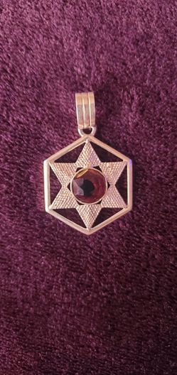 Star of David pendant features a textured filigree design centered around a Purple garnet gemstone