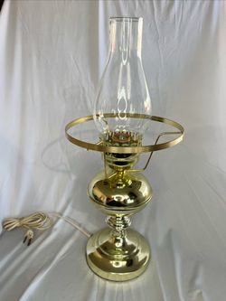 Vintage-style polished brass electric hurricane table lamp featuring a clear glass chimney shade.