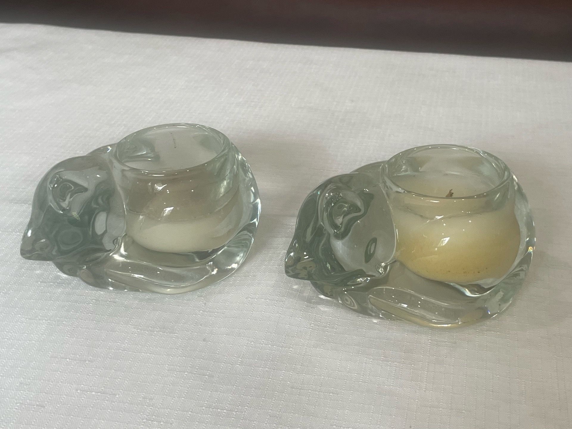 Pair of clear molded glass sleeping cat votive candle holders.