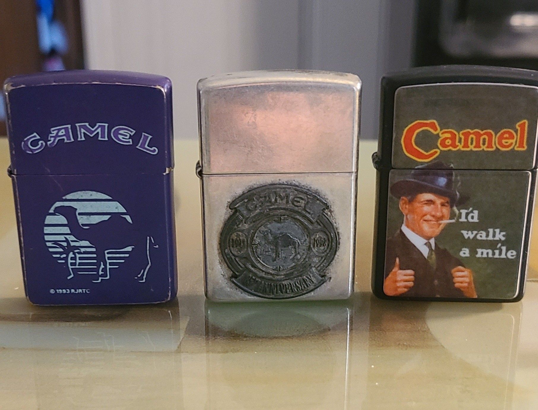 Vintage Zippo Joe Camel lighters. Purple one is 1993, the I'd walk a mile is 1995, and the other one is the 85th Anniversary one.