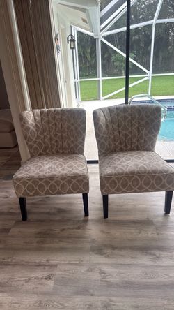 Two light brown/gray accent chairs.