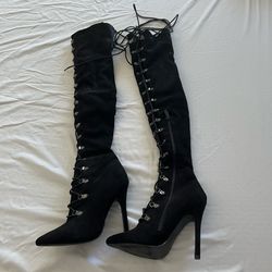 Size 6.5/7 women’s black faux suede, lace-up thigh-high boots feature a pointed toe and stiletto heel