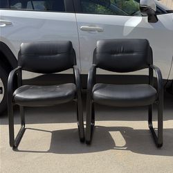 Two black leather-looking  chairs