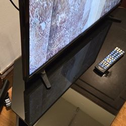 Entertainment center made of glass and metal includes TV. The TV has a 28" screen.