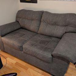 Charcoal Loveseat With White Stitched Pattern.