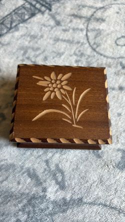 This vintage Swiss wood music box features a hand-carved Edelweiss flower on its hinged lid