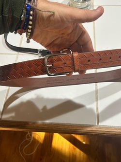 brown leather belt features a detailed woven diamond pattern and a polished silver-tone buckle.
