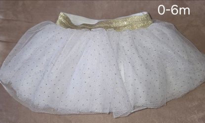 Sparkly white tutu skirt has gold glitter dots. Gold elastic waistband. Baby size 0-6m.