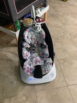 Clean 4moms MamaRoo baby bouncer. Has a floral patterned seat insert. Has a 5-point harness for safety. Comes with hanging toys. Electronic control pa