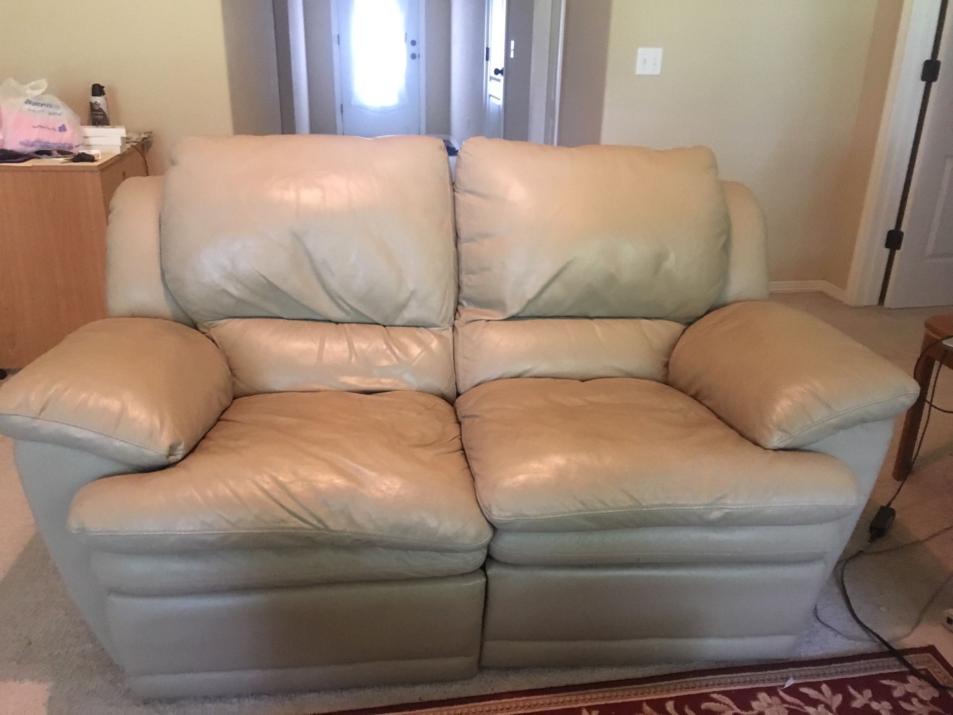 Italian leather reclining sofa and loveseat, coffee table 2 end tables with lamps and a area rug.