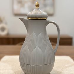 White pitcher with gold accents, perfect for serving beverages.