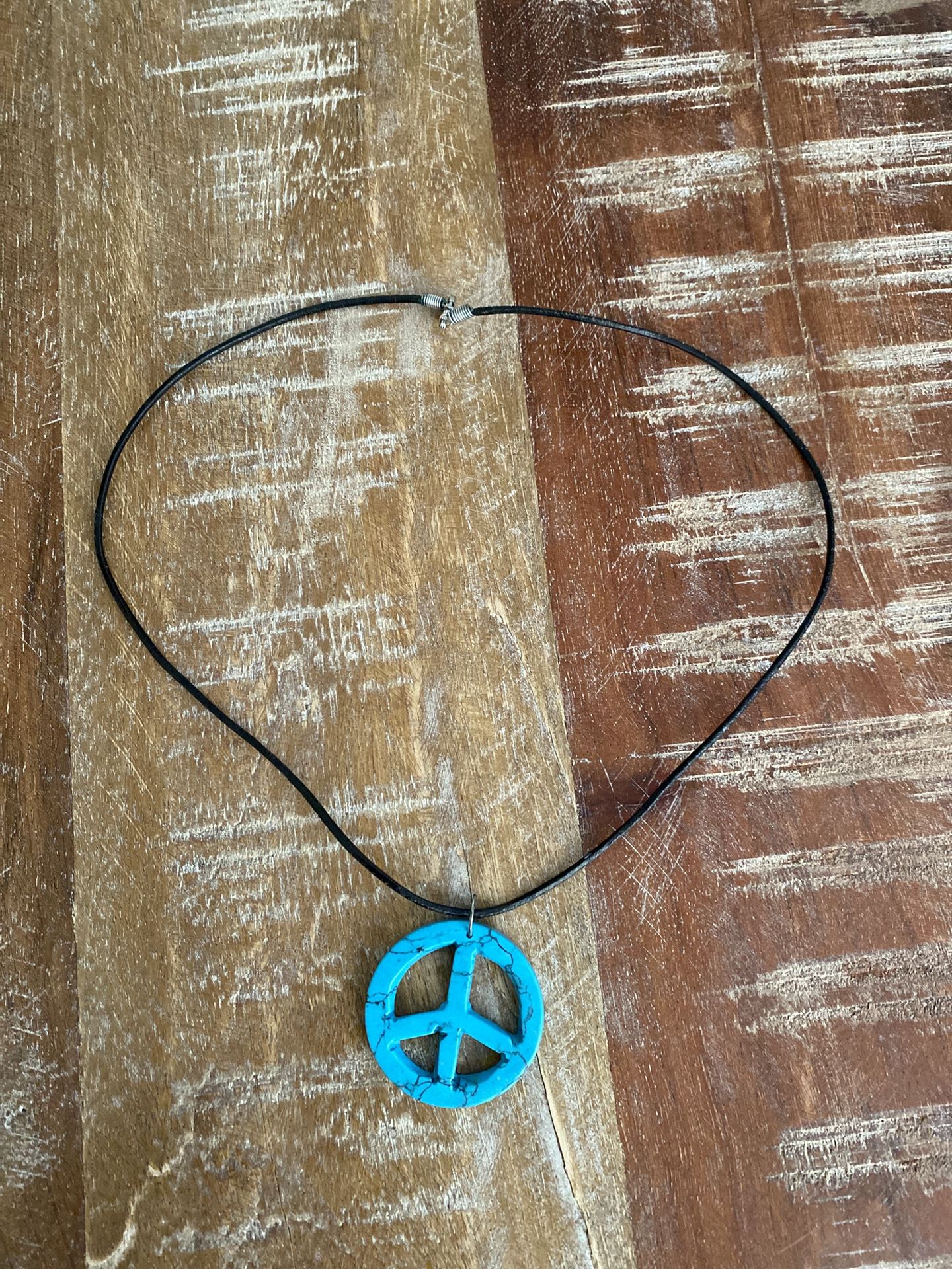 For sale simulating dyed howlite turquoise stone peace sign black cord necklace.
