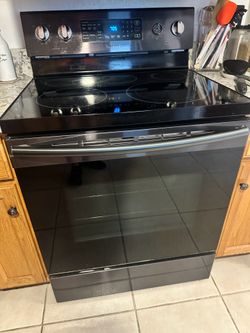 Samsung 30-inch freestanding electric range in black stainless steel, featuring a 5.9 cu. ft. oven and a glass