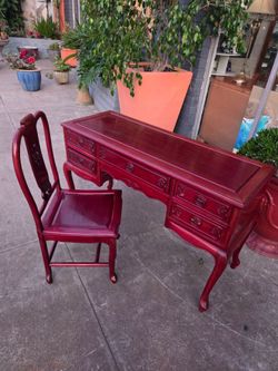 The Oriental-style desk and chair set is crafted from rosewood and features a dark red lacquer finish.