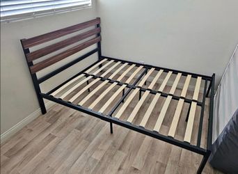 Newer full size platform bed frame features a minimalist black metal structure paired with a rustic bamboo headboard.