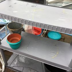 A Nice Gray Shelf With  Three Shelves And Many  Garden  Items
