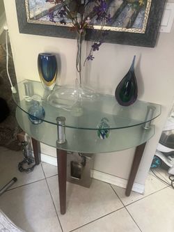 two-tiered glass side table with wooden legs and metal accents