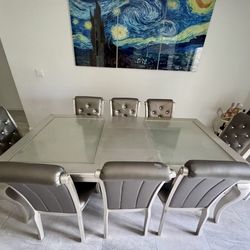 Modern dining table set with 6 chairs and glass top.