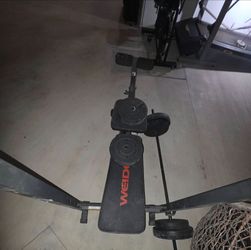 banco de pesas multifuncional con soporte para barra y extensión de piernas.