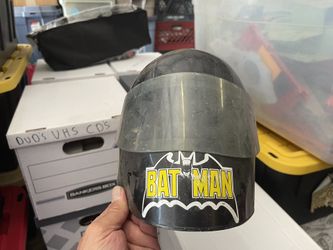 vintage 1964 Ertl Batman toy motorcycle helmet.  Type: Collectible toy helmet with visor. Era: Produced in 1964. Design: Features a black shell with a