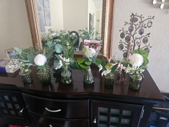 Table flowers in green glass bud vases different shapes.