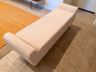 Upholstered bench in cream boucle fabric .