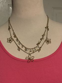 gold-tone double-layered charm necklace featuring wire-frame floral pendants and leaf charms