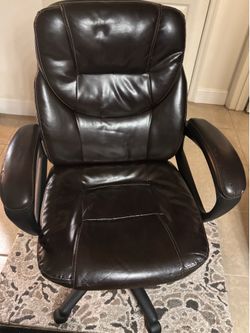 Comfortable brown leather office chair with armrests .