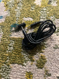 Se trata de un cable de extensión de audio auxiliar negro, generalmente con conectores de 3.5 mm o 2.5 mm.