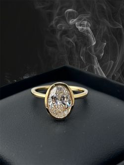 Yellow gold ring featuring a bezel-set oval-cut center diamond