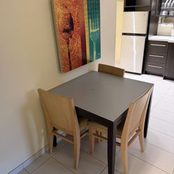 Three chairs, a table, and a decorative painting on sale.