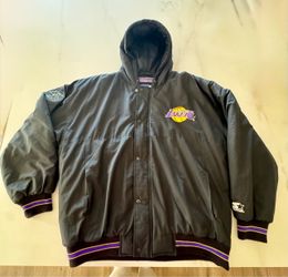 This vintage black Los Angeles Lakers Starter Jacket features a hooded design highlighted by the classic embroidered purple and gold team basketball l