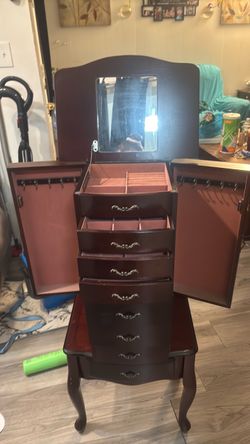 freestanding wooden jewelry armoire with a mirror, drawers, and side-opening doors
