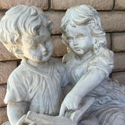 Statue Of Little Girl And Boy Reading On Bench