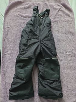 Pantalon de nieve con tirantes de color negro para niños, diseñados para actividades de invierno. MARCA COLUMBIA..
Black snow pants with suspenders fo