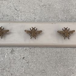 wall-mounted coat rack with decorative bee-shaped hooks. It is a functional and decorative home accessory