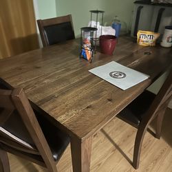 A wooden table with six wooden and brown leather chairs