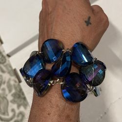 This bracelet features a series of iridescent blue, green, and purple faceted glass beads in varied coin and marquise shapes. The piece is likely vint