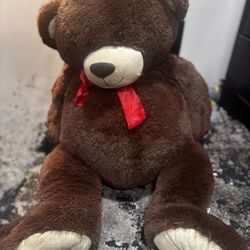 This is a modern jumbo brown teddy bear with a red ribbon.