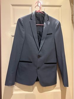 Tailored single-breasted blazer with notch lapel. Black trim accents on lapel and pockets. Two-button front with welt chest pocket. Smooth dark lining