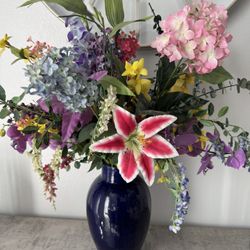 Beautiful faux floral arrangement. Has pink hydrangeas, a big pink and white lily, purple orchids, yellow flowers, and lots of greenery. Comes in a gl