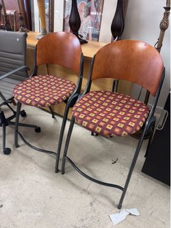 Pair of foldable design barstools with a distinct curved wooden backrest and a metal frame