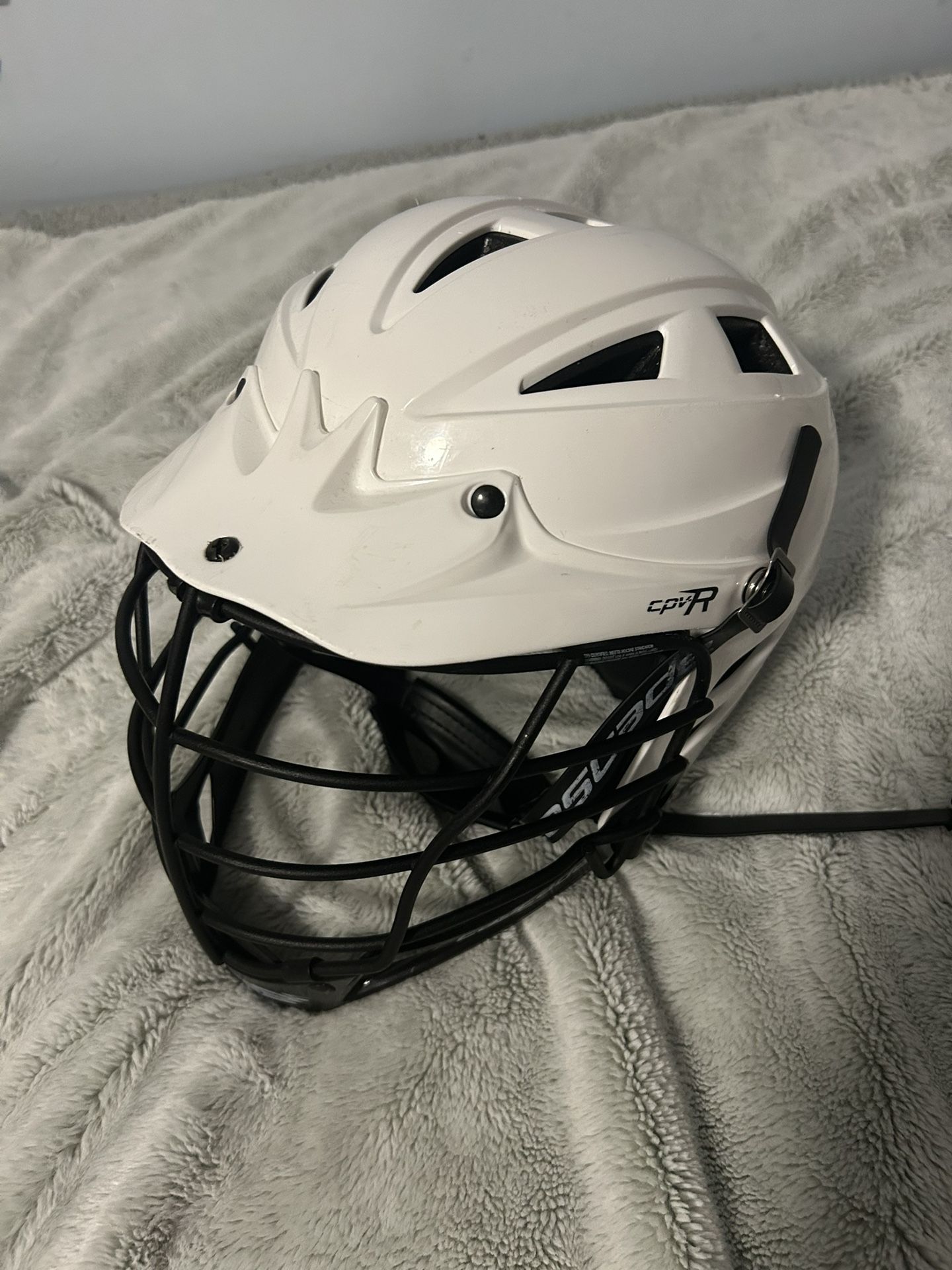 Cpv-r cascade white lacrosse helmet with a black cage and black chinstrap.