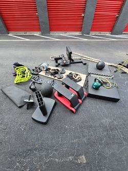Large lot of used fitness equipment including kettlebells, medicine balls, a TRX slam ball, BOSU ball, resistance bands, gymnastic rings with straps, 
