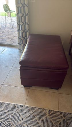 storage ottoman upholstered in a rich burgundy/oxblood leather.