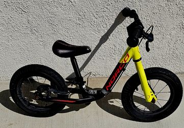 Norco Ninja 12 Run children's balance bike, featuring a black frame with red lettering and a bright yellow front fork.