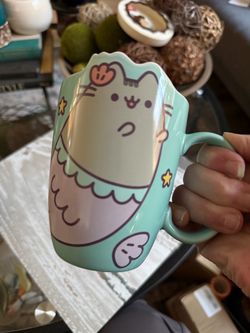 Pusheen Mermaid Die-Cut Mug   Adorable ceramic mug is mint green with a Pusheen mermaid design. It has a sculpted rim shaped like cat ears and feature