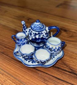 A blue and white miniature ceramic tea set with floral decoration.