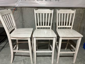 Three distressed white bar stools